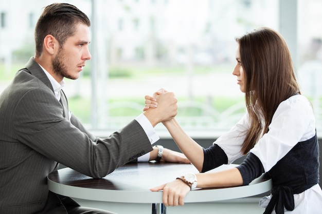 Business and office concept businesswoman and businessman arm wrestling during meeting in office