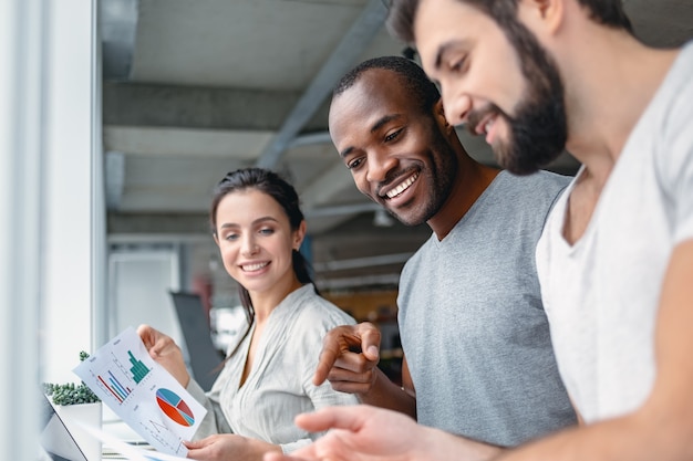 Business and office concept smiling team discussing achievements looking at charts