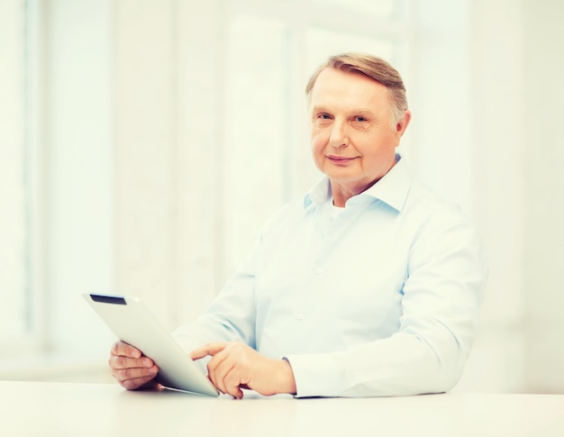 business, office, oldness, school and education concept - old man wearing eyeglasses with tablet computer at home