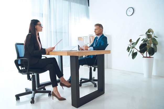 Business partners with papers discussing work at workplace in office