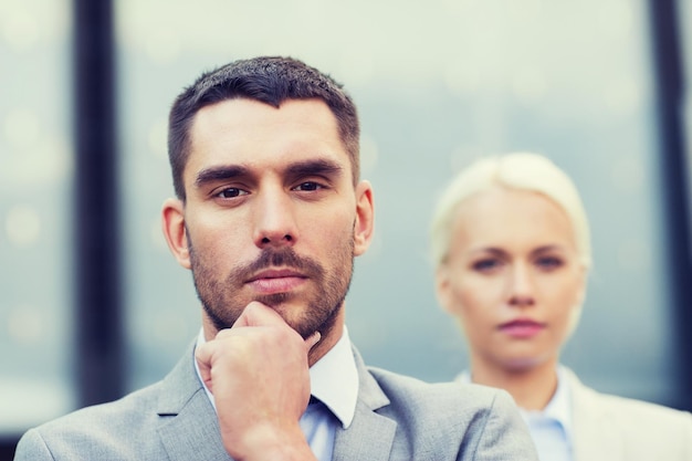 business, partnership, success and people concept - businessman and businesswoman standing over office building