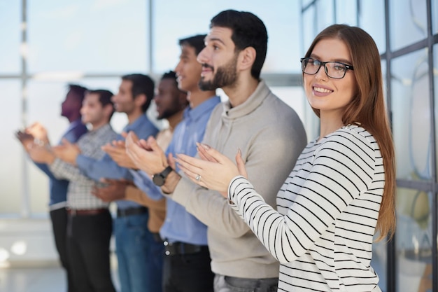 Business people applaud in a conference room standing in a row side view