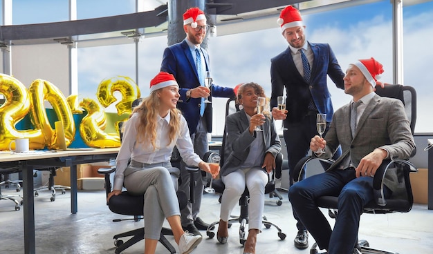 Business people are celebrating holiday in modern office drinking champagne and having fun in coworking Merry Christmas and Happy New Year 2023