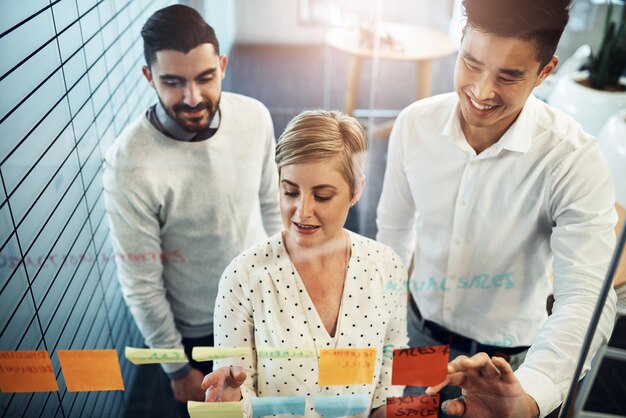 Photo business people brainstorming and planning with glass board project strategy or sticky note in office lens flare diversity and employees in meeting for writing ideas agenda or collaboration