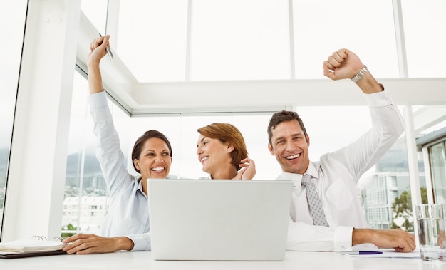 Business people cheering in front of laptop at office