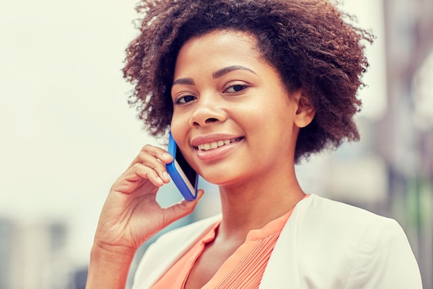 business and people concept - young smiling african american businesswoman in city