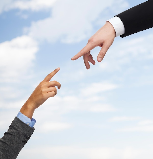 business, people, cooperation and connection concept - close up of woman and man hands trying to connect over blue sky background