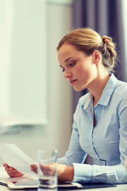 business, people and crisis concept - businesswoman sitting sad and reding document in office