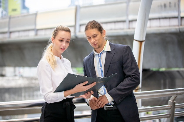 Business people discussing over clipboard and while walking outside office