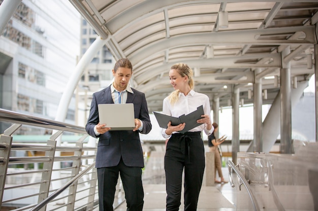 Business people discussing over clipboard and while walking outside office