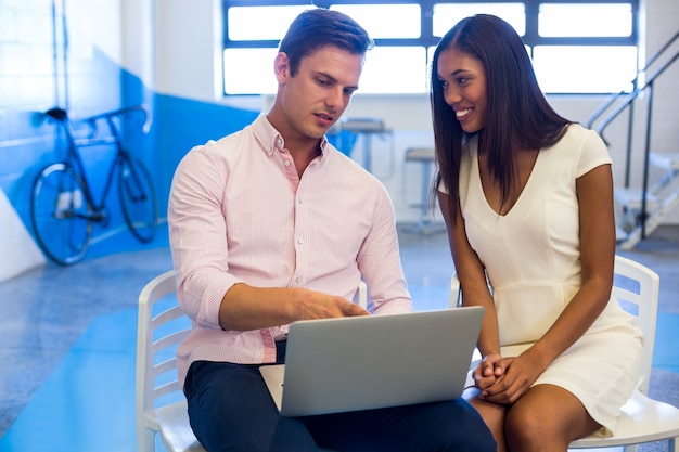 Business people discussing over laptop