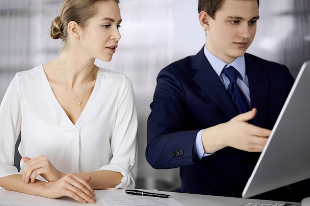 Business people discussing something while sitting in office Focus at businesswoman while talking to her male colleague Teamwork and meeting concept