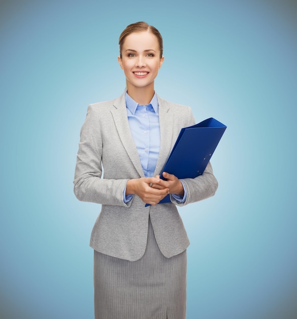 business, people and education concept - smiling young businesswoman with holding over blue background