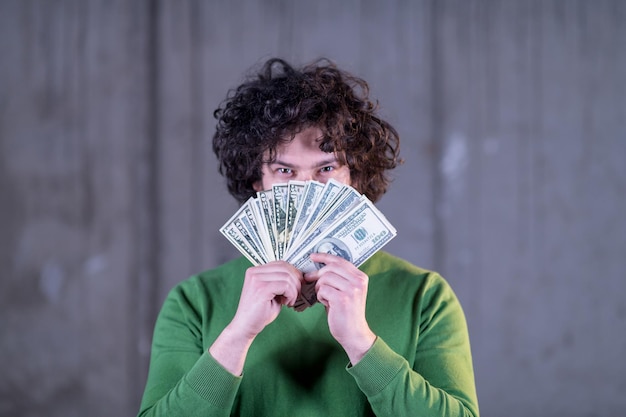 business, people and finances concept  happy young business man displaying a spread of american dollar cash money in new startup office