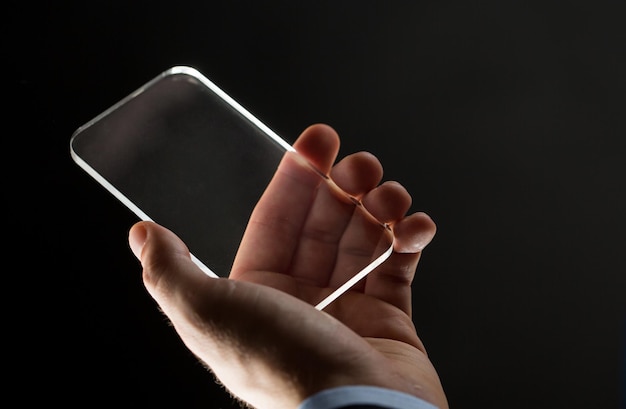 business, people and future technology concept - close up of businessman hands with transparent smartphone over black