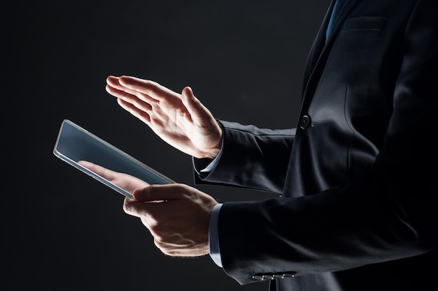 business, people and future technology concept - close up of businessman hands with transparent tablet pc computer over black