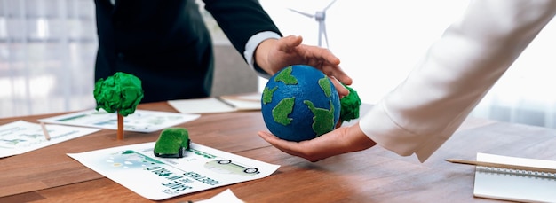 Business people holding paper earth together over office table Green corporate company implementing ecofriendly policy to reduce CO2 emission and conserve green environment concept Trailblazing