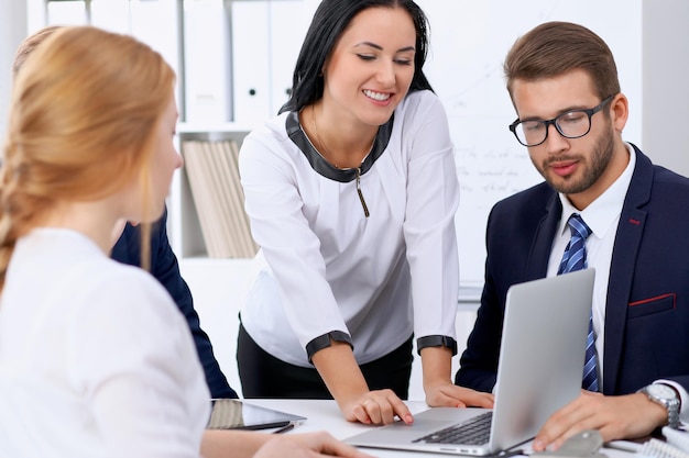 Business people at a meeting in the office. Focus on woman pointing into laptop.