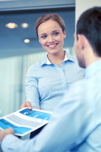 business, people, meeting and teamwork concept - smiling businesswoman giving papers to man in office