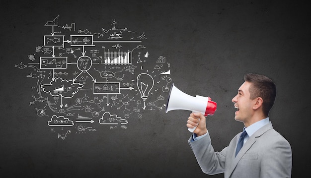 business, people and public announcement concept - happy businessman in suit speaking to megaphone and scheme over dark gray concrete wall background