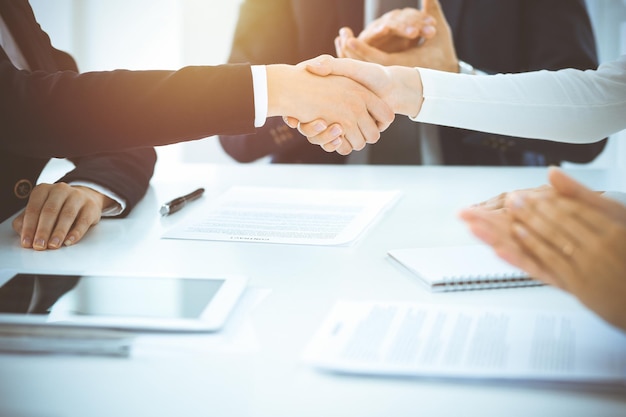 Business people shaking hands finishing up meeting or negotiation in sunny office Business handshake and partnership concepts