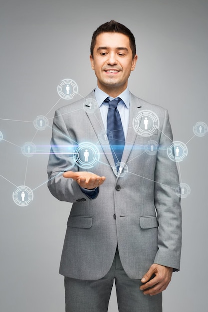 business, people, technology, connection and communication concept - happy businessman in suit showing network contacts over gray background