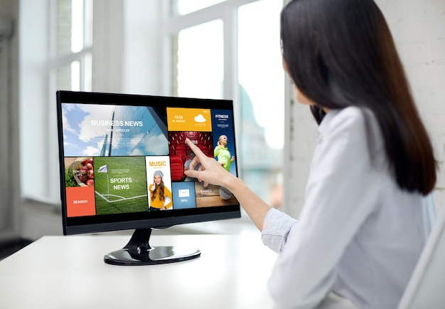 business, people, technology and mass media concept - close up of woman pointing finger to news application on computer monitor in office