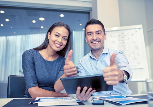 business, people, technology and teamwork concept - smiling businessman and businesswoman with tablet pc computer showing thumbs up gesture meeting in office