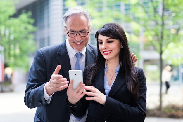 Business people using a mobile phone in front of their office