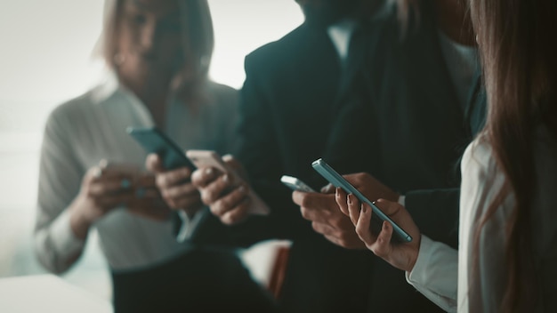 Business people using mobile phones together standing in office close up shot of human hands holding...