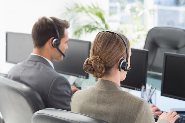 Business people with headsets using computers 