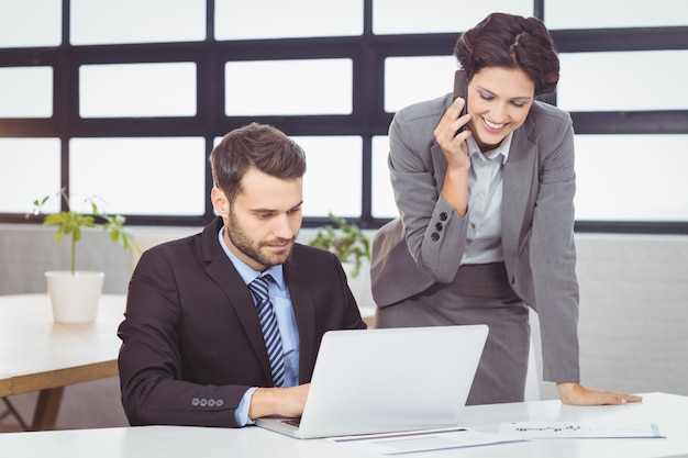 Business people with mobile phone and laptop in office