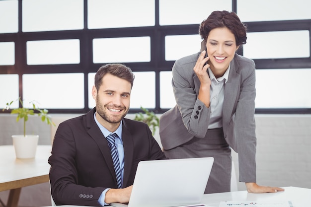 Business people with mobile phone and laptop in office