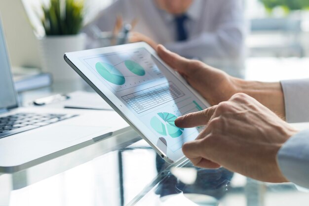 Photo business person analyzing financial statistics displayed on the tablet screen