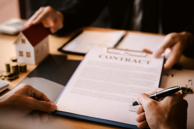 Photo business person asking customer to sign papers on table