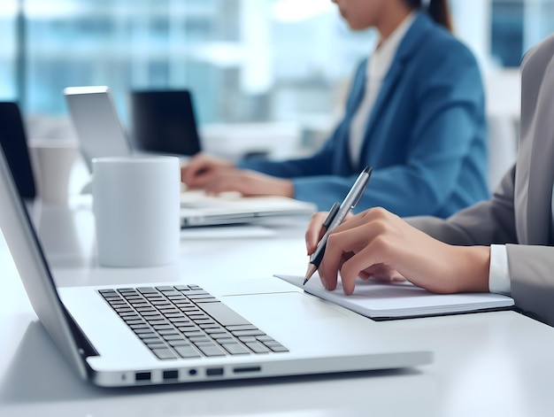 Business person using laptop and man or woman operating laptop and making a note Business Office