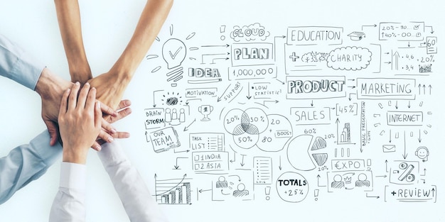 Business plan concept with human hands in a pile and handwritten sketch of business indicators and steps on light surface