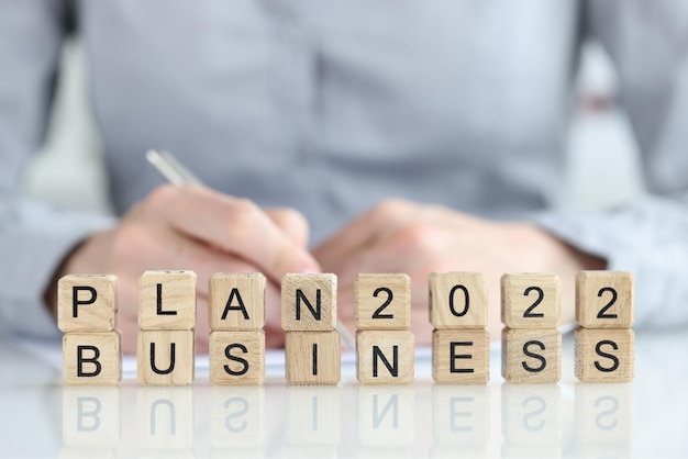 Business plan text on wooden cubes and businesswoman with pen development of small and medium