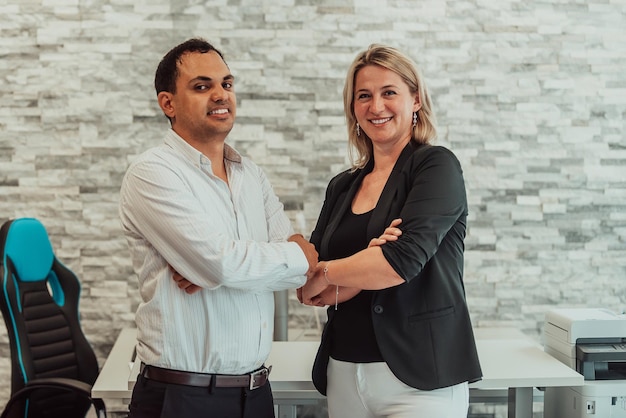 Business portrait of Indian man and woman with crossed arms in modern office.