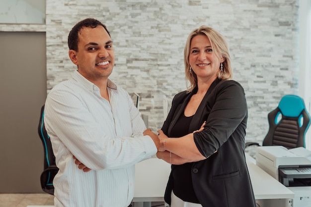 Business portrait of Indian man and woman with crossed arms in modern office.