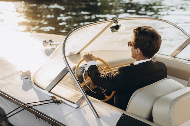 Business portrait of young man in suit and sunglasses posing on a yacht