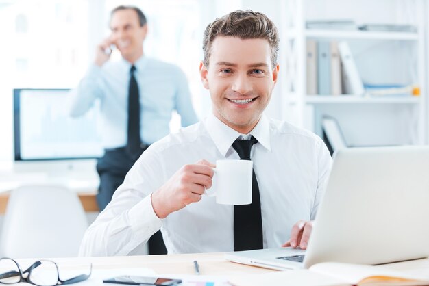 business professional.cheerful businessman in formalwear holding a cup of coffee 