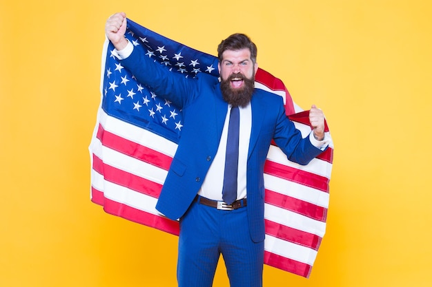 Business professional. Successful business owner holding american flag on yellow background. Happy business man celebrating independence day. Bearded man in formalwear enjoying success in business.