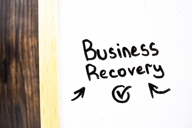 BUSINESS RECOVERY text concept on white board with checkmark and arrows