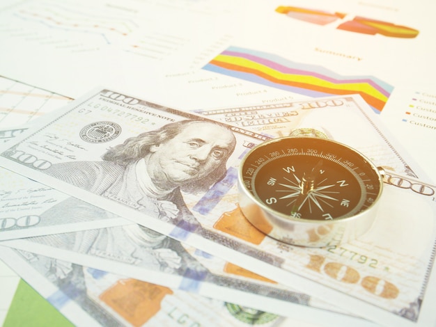 Business report chart and Financial graph analysis with dollar money and compass on table