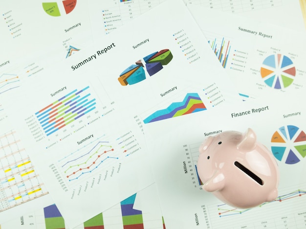 Business report chart and Financial graph analysis with Pink piggy bank on the table.