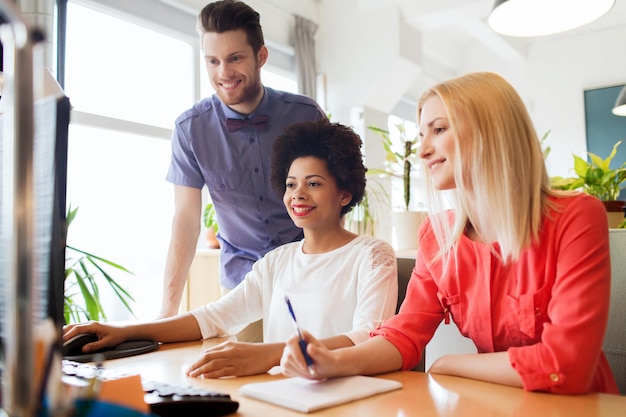 business, startup and people concept - happy creative team networking with computer in office