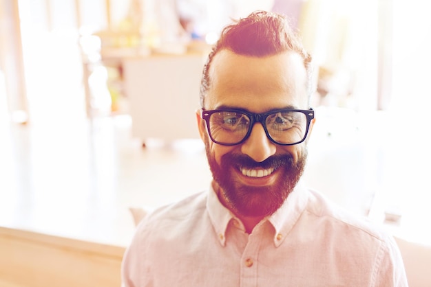 business, startup, and people concept - happy smiling latin man with eyeglasses and beard at office