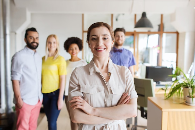 business, startup, people and teamwork concept - happy young woman over creative team in office