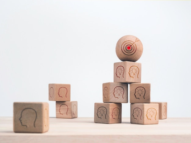 Business strategy and action plan concept. Goal target icon on the wood sphere on the top and wooden cube blocks pile with business strategy symbols on wooden table on white background.